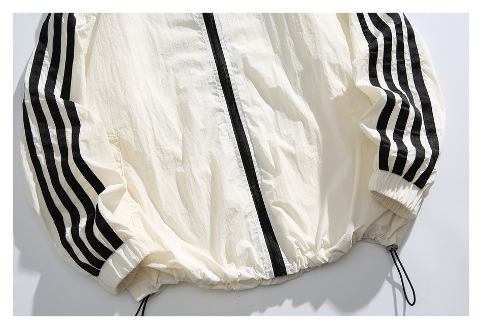Close-up of the ivory jacket's lower front, black zipper, striped sleeves, elastic cuffs, and hem drawcords.