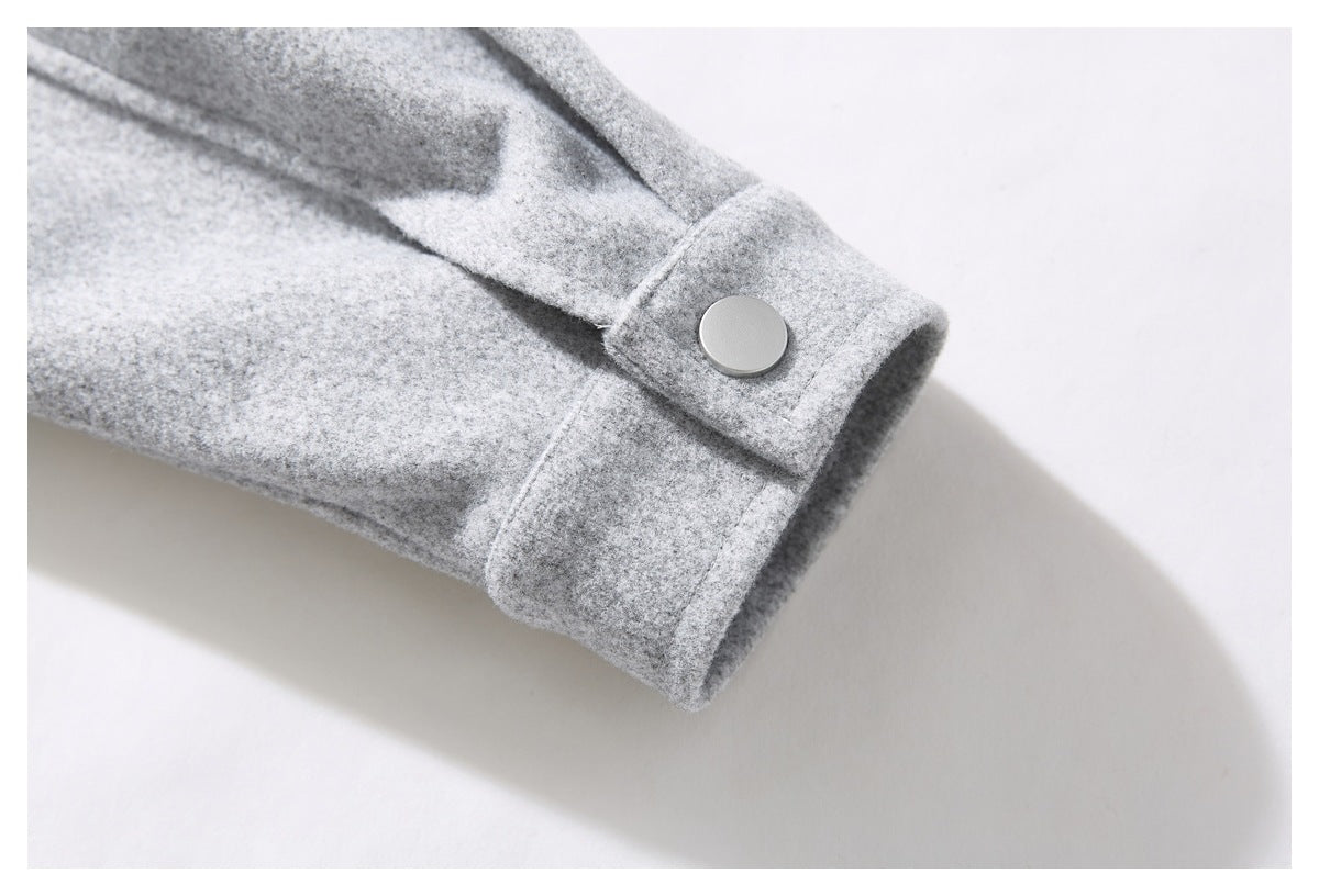Close-up of a light gray coat sleeve cuff with a large silver snap button.
