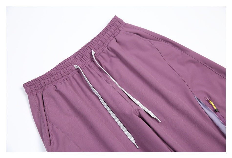 Close-up of mauve pants showing the elastic waistband, gray drawstrings, and part of a zip pocket.