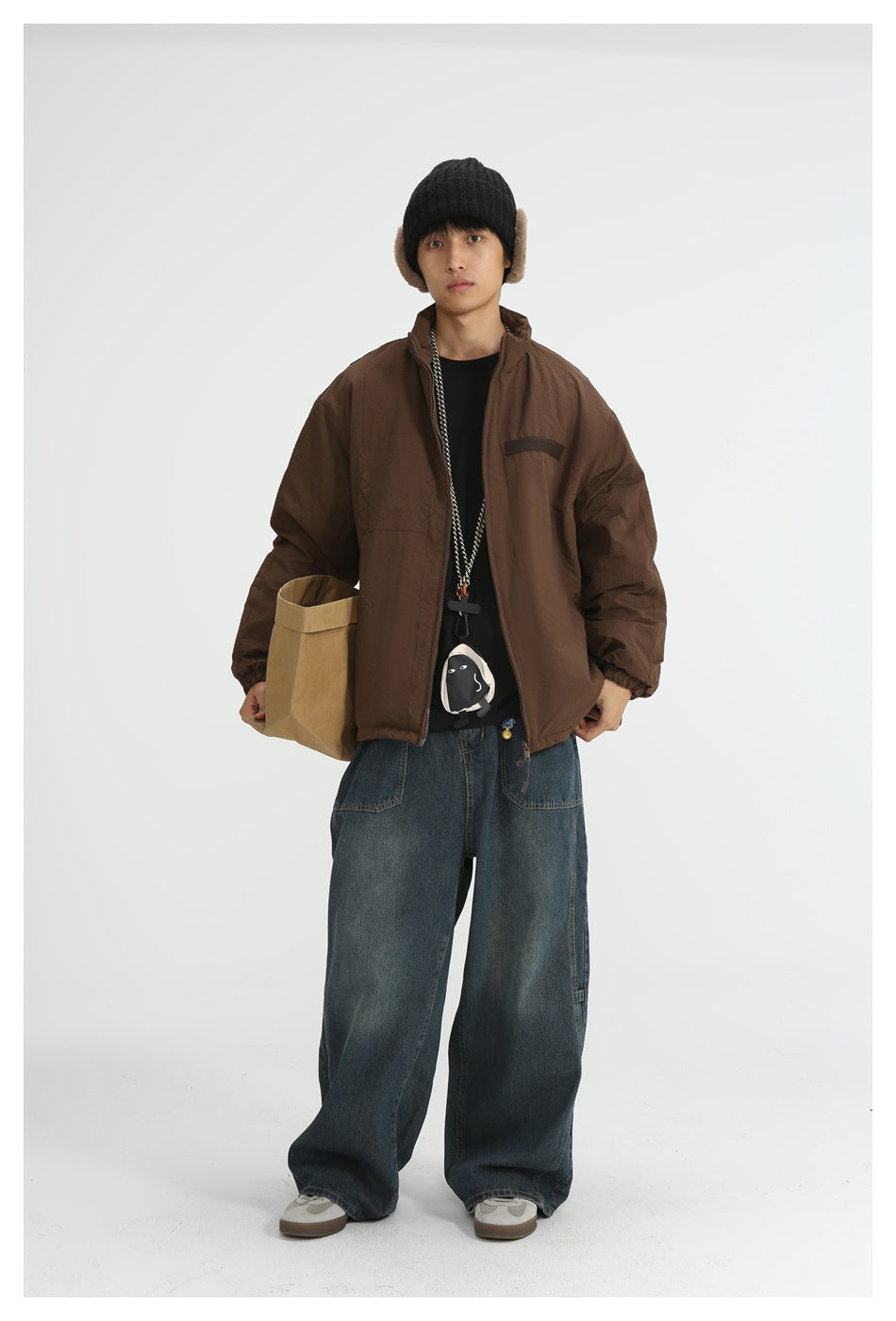 Model wearing brown zip jacket with black beanie, black tee and wide-leg jeans, front view
