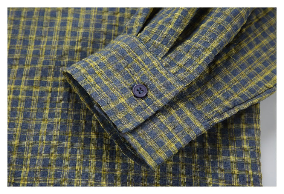 Close-up of a buttoned cuff on a blue-gray and mustard plaid shirt.
