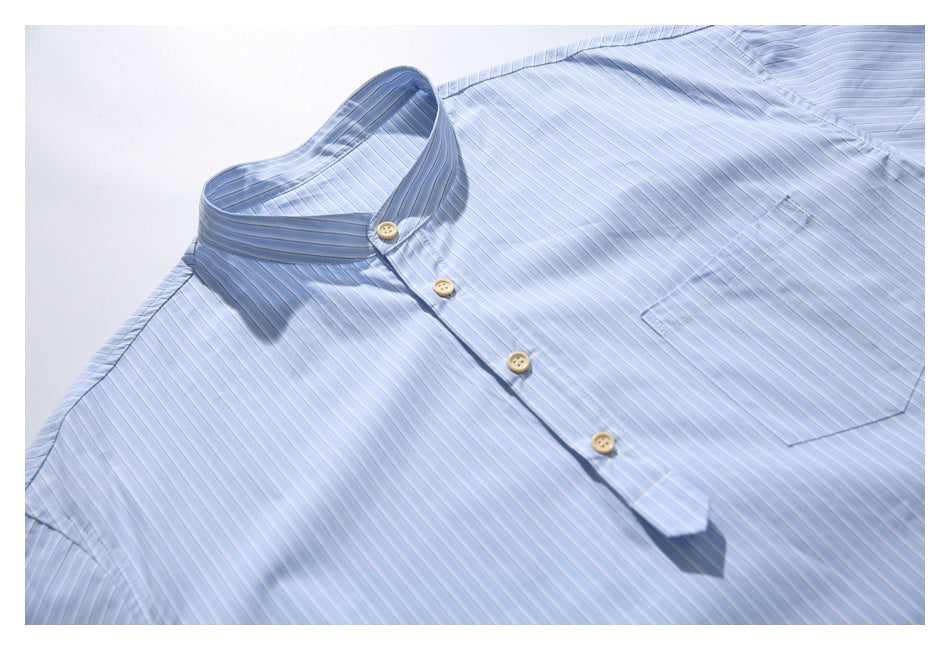 Angled flat-lay view of a light blue striped shirt with a stand collar, button placket and chest pocket.