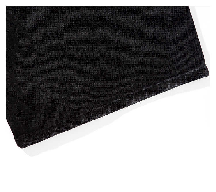 Close-up of the stitched hem on black denim fabric.