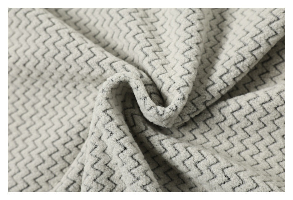 Close-up of folded off-white fabric with a gray zigzag pattern and soft, textured surface.