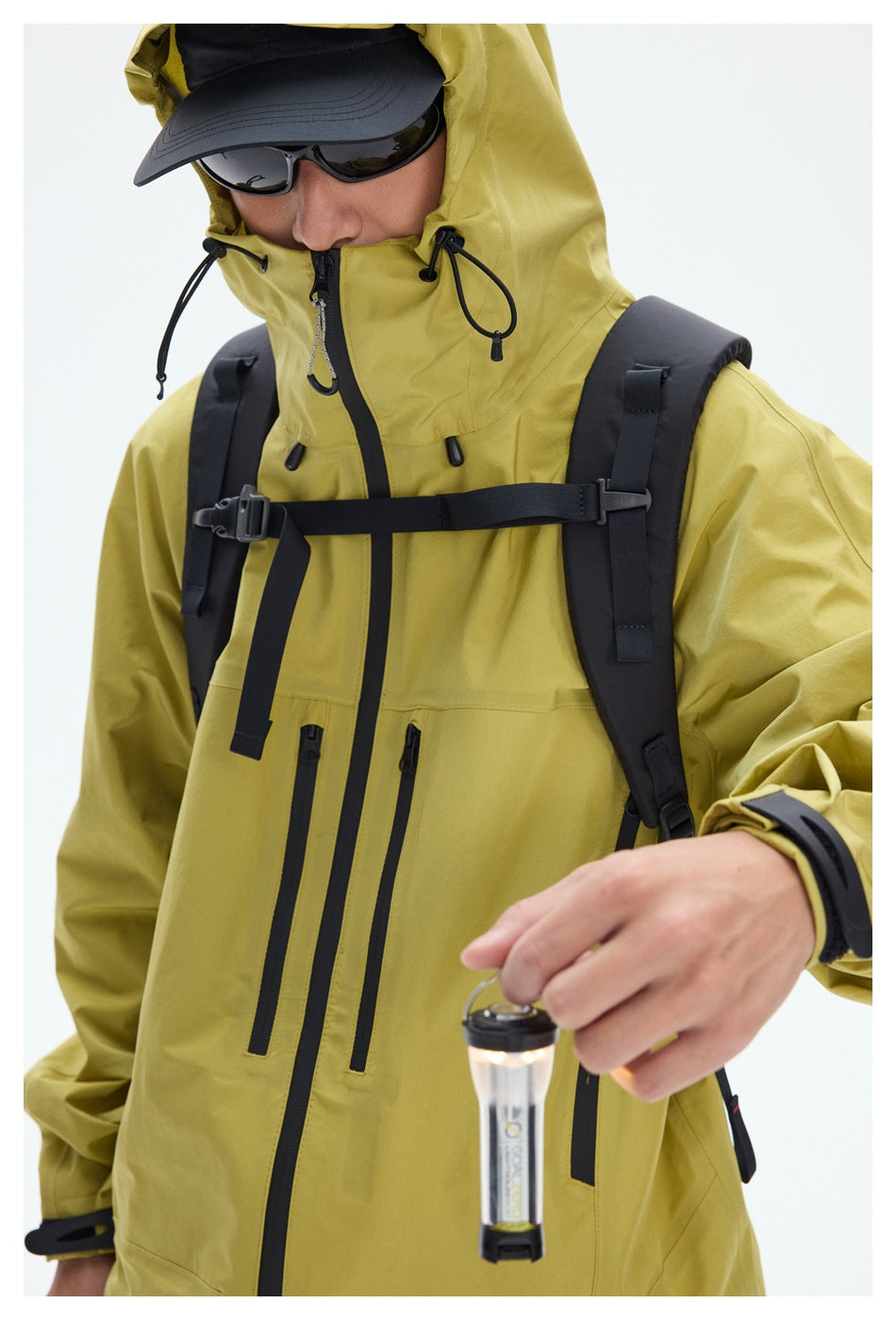 Close view of a yellow hooded jacket showing drawcords, black front and chest zippers, and adjustable cuffs.