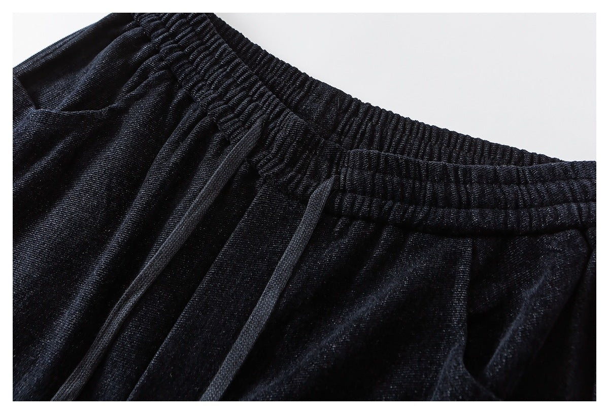 Close-up of black pants with a gathered elastic waistband and two black drawstrings.