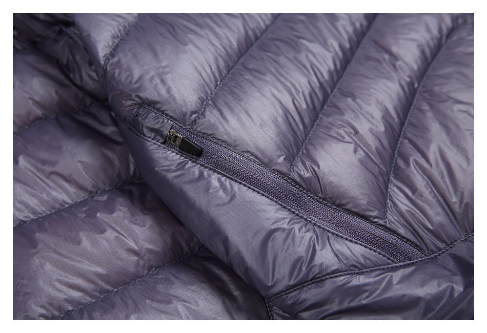 Close-up of a dark purple quilted jacket showing a diagonal zipper and padded sections.