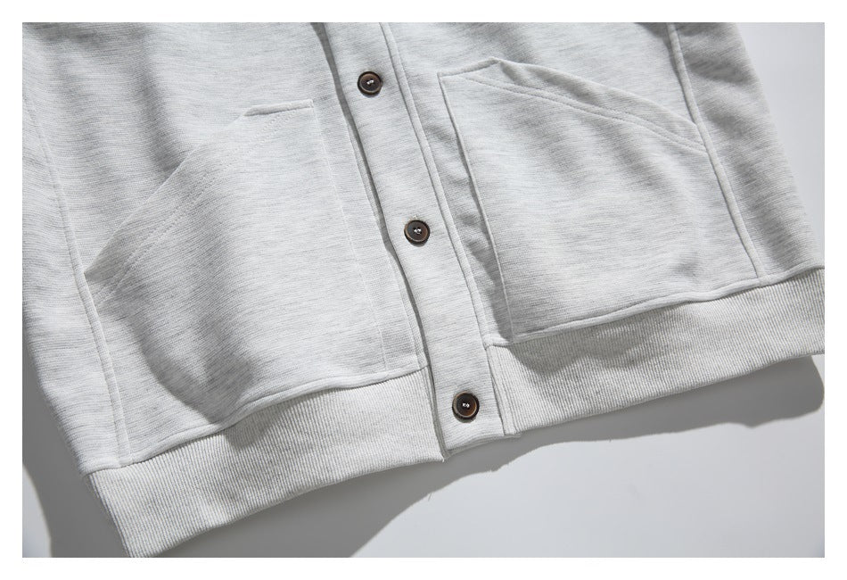 Close-up of the cardigan's two front patch pockets, dark buttons, and ribbed hem.