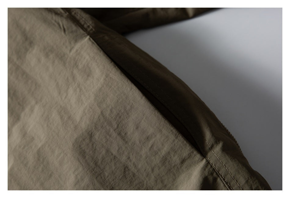 Close-up showing stitched seam and overlapping panels on an olive-brown jacket.