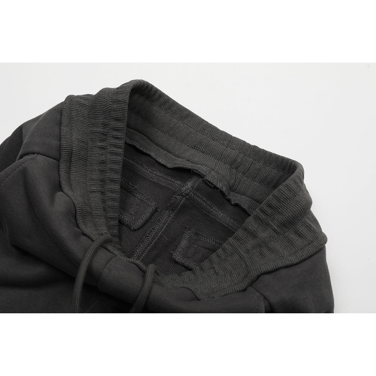 Inside view of charcoal pants showing the elastic waistband, drawstring, and stitched interior seams.
