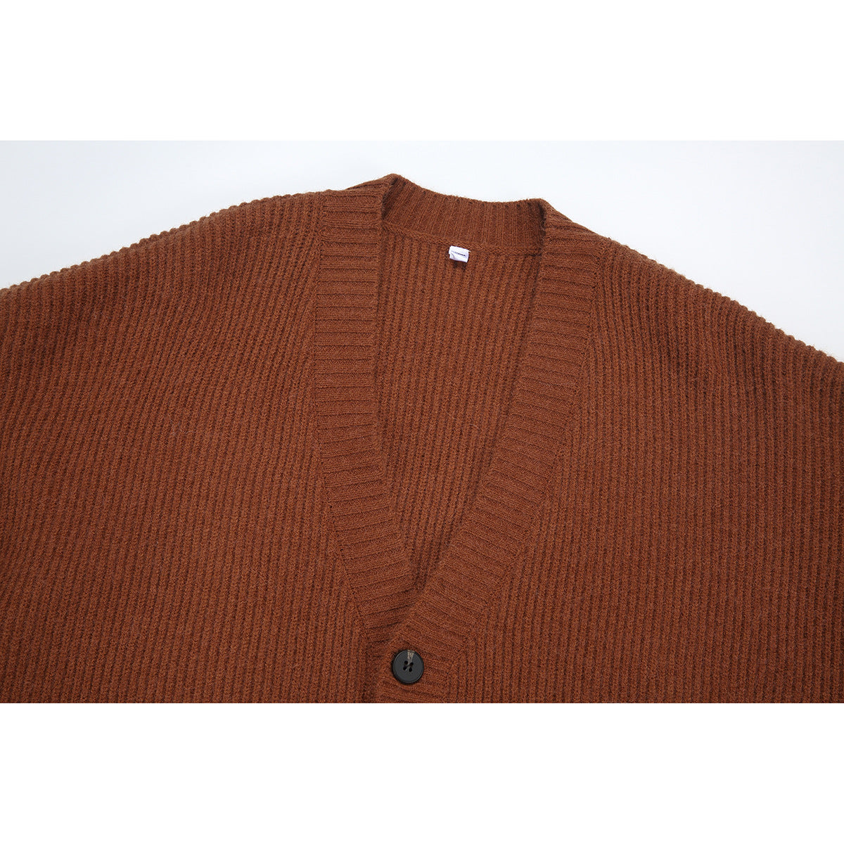 Close-up of a rust-brown ribbed cardigan showing its V-neck edge and dark button.