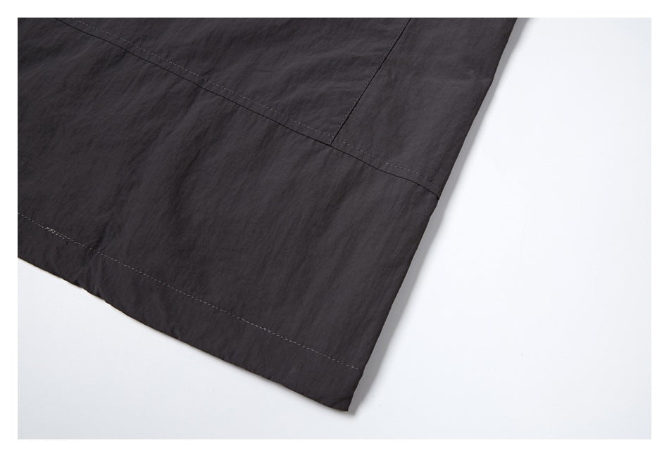 Close-up of charcoal fabric panels and stitched seams along a garment hem.