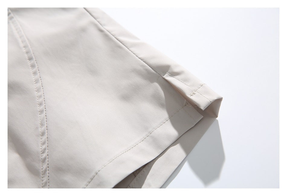 Close-up of the stitched hem and seams on light gray shorts.