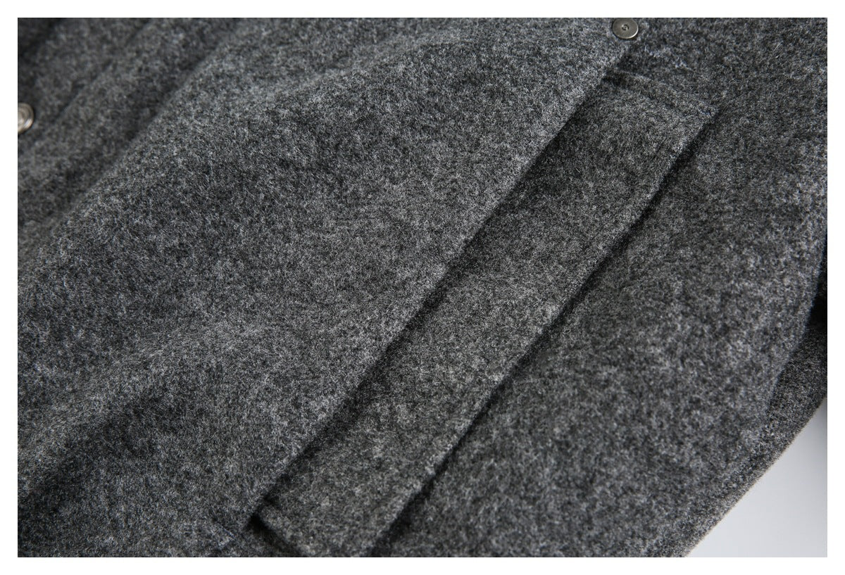 Close-up of a charcoal gray garment pocket flap and dark metal snap button.