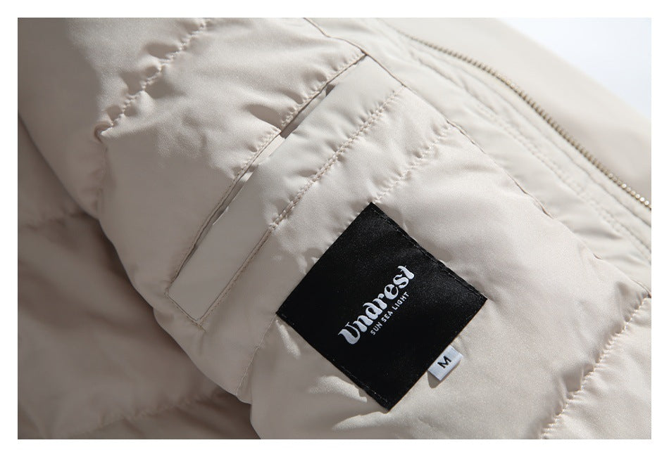 Close-up of a cream padded jacket showing a black sewn-in brand label, size M tag, stitching, and zipper.
