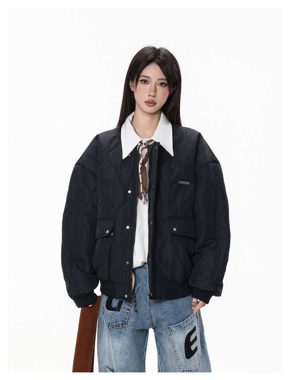 Model wearing a black quilted bomber jacket with snap-front closure and flap pockets, shown from the front.