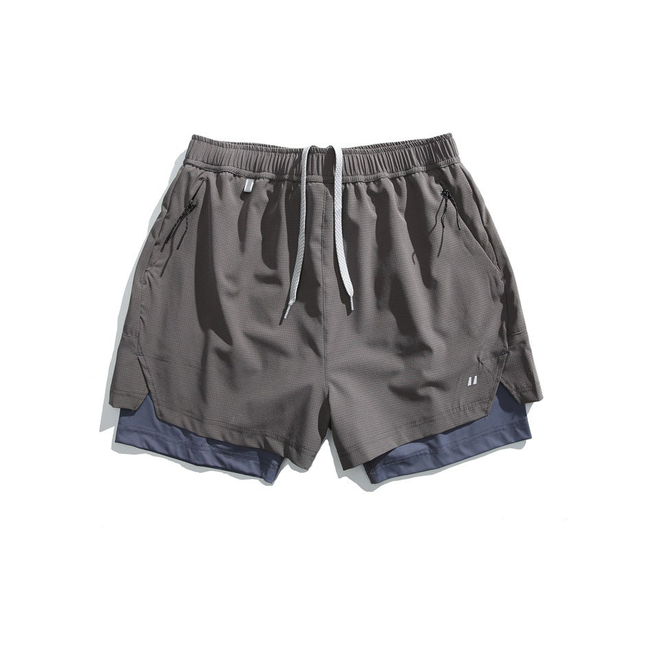 Dark gray double-layer athletic shorts with blue-gray inner layer, drawcord and zip pockets, flat lay