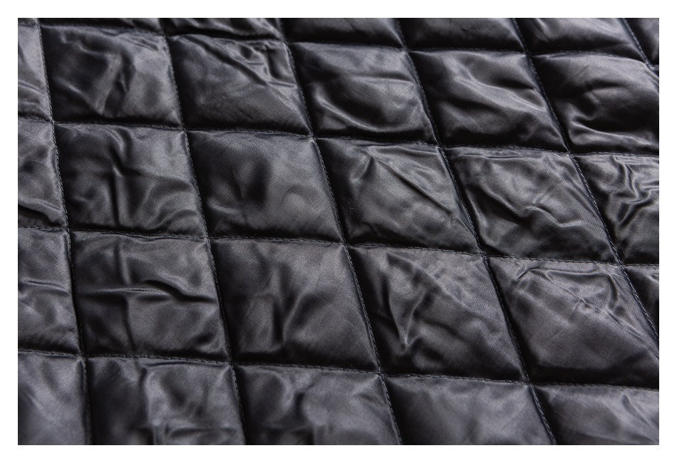 Close-up of black fabric with a glossy finish and rectangular quilted stitching.