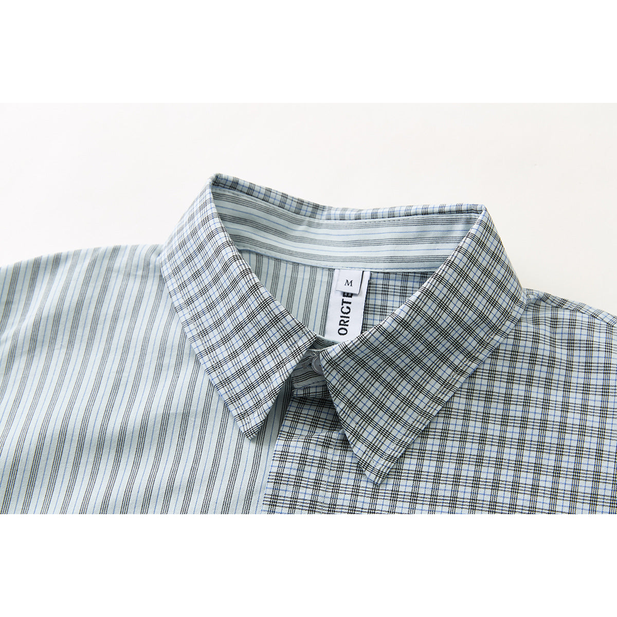 Close-up of a light blue and white striped shirt collar with a checked pattern and a visible neck label.