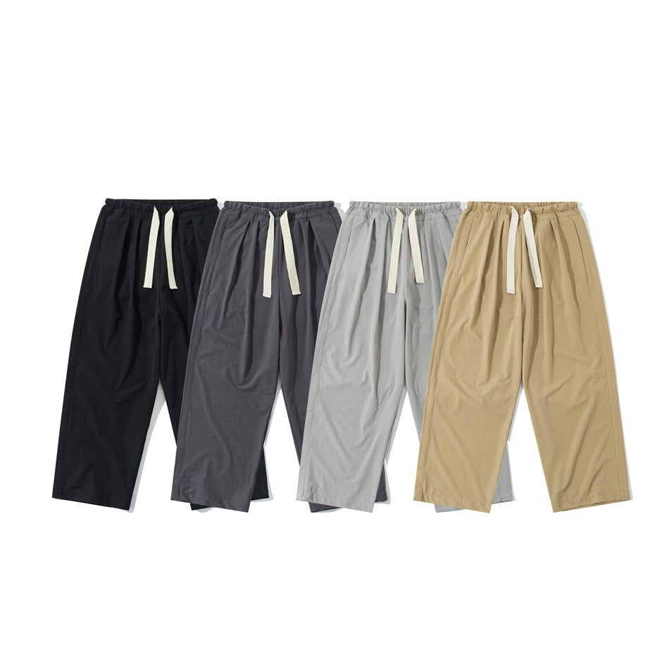 Four pairs of wide-leg trousers with elastic waists and cream drawstrings in black, charcoal, light gray, and tan.