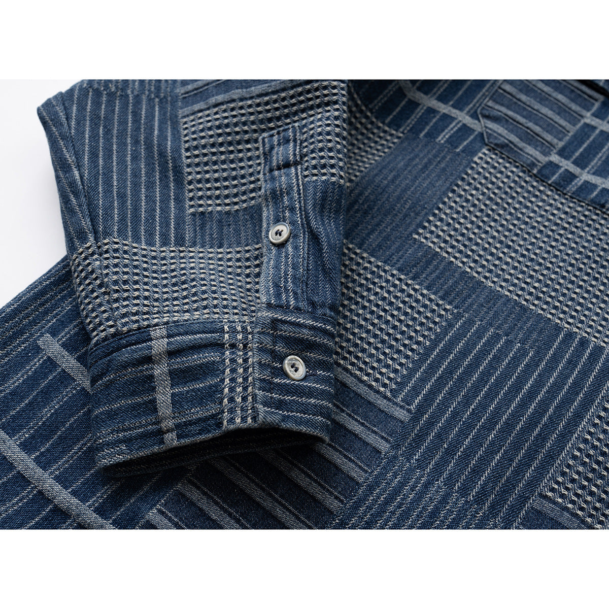 Close-up of a blue patterned shirt sleeve and buttoned cuff beside the textured front panel.