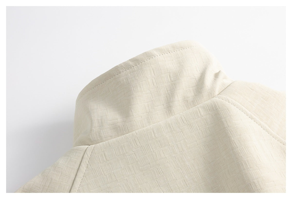 Close-up of the cream jacket's raised collar and textured stitched fabric.