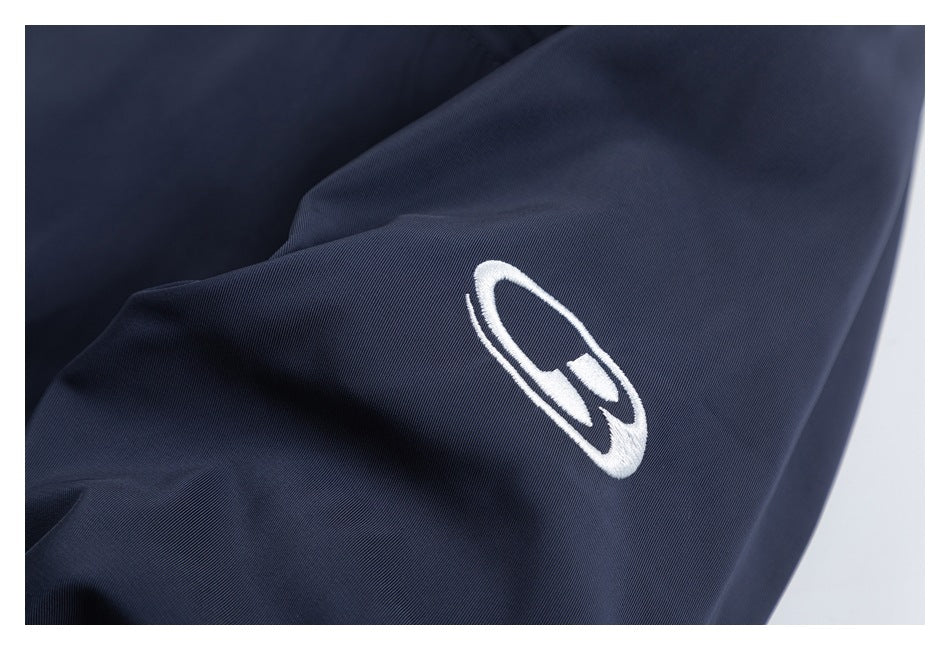 Close-up of a white embroidered symbol on a dark navy garment sleeve.