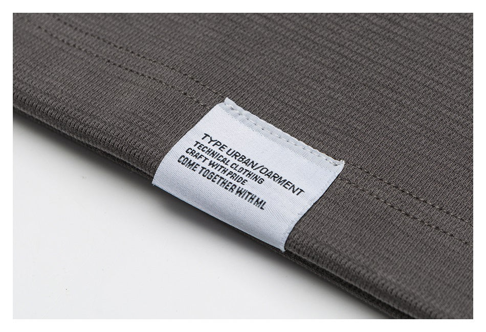 Close-up of a sewn white garment label with English text on charcoal fabric.
