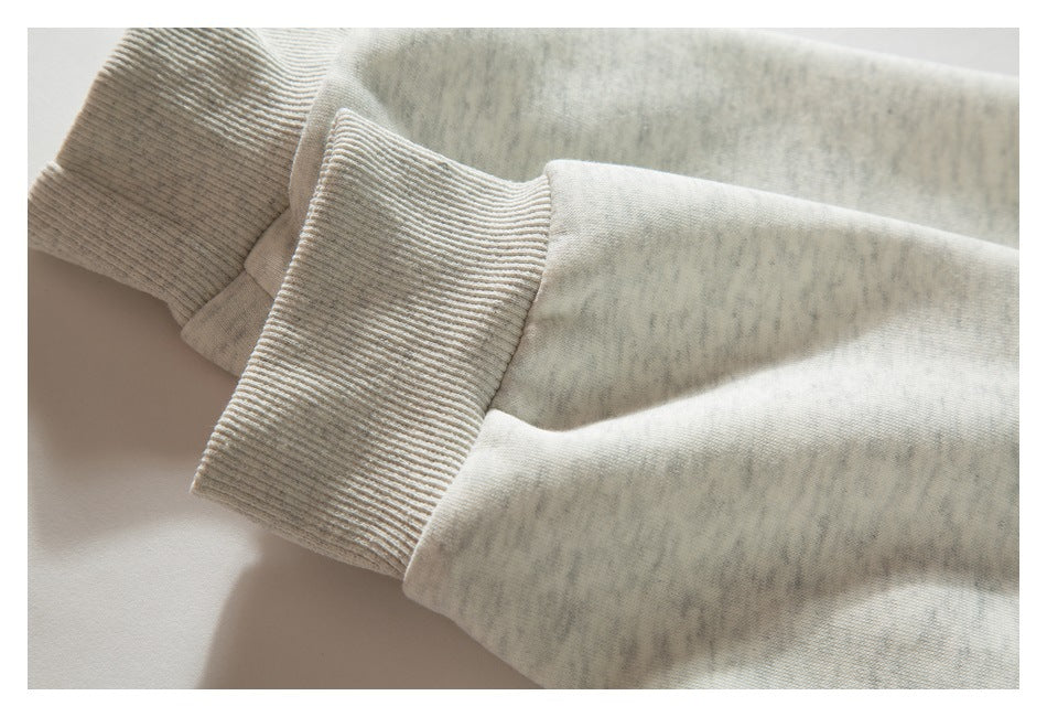 Close-up of a ribbed cuff on the sleeve of a light gray heathered sweatshirt.