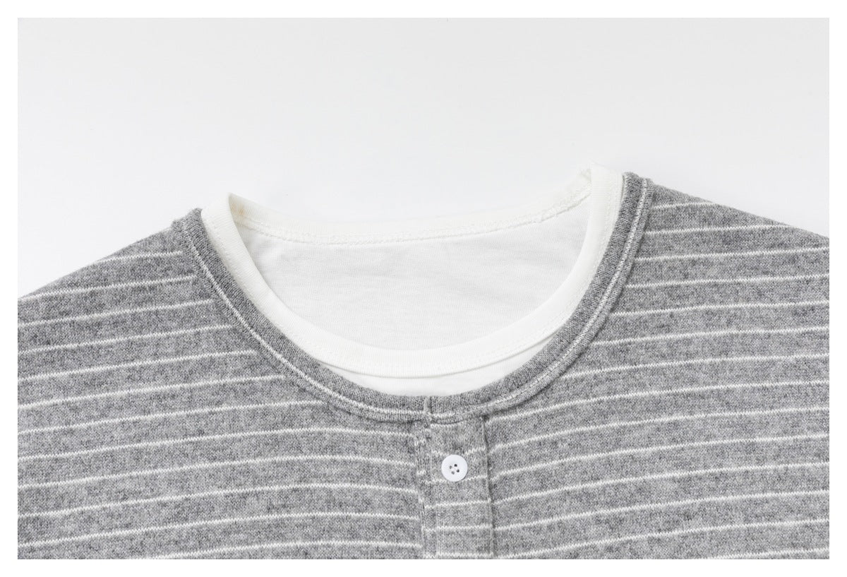 Close-up of the gray-and-white striped top's layered white crew neckline and button placket.