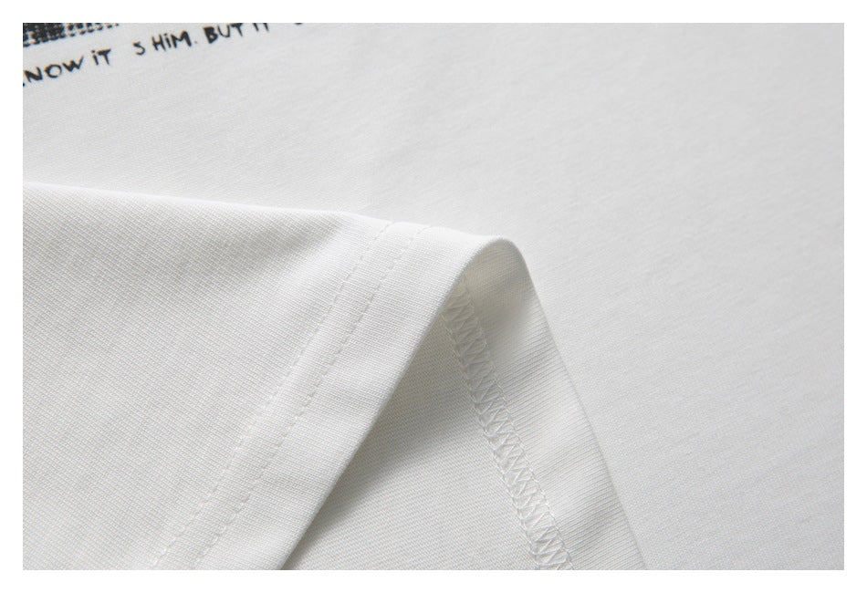 Close-up of the white T-shirt fabric and finished seam, with part of a black graphic visible.