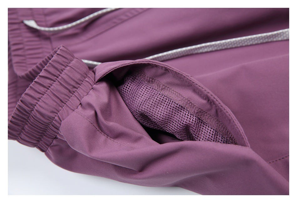 Close-up of purple trousers showing an elastic cuff, mesh-lined pocket, and light-colored drawcord.