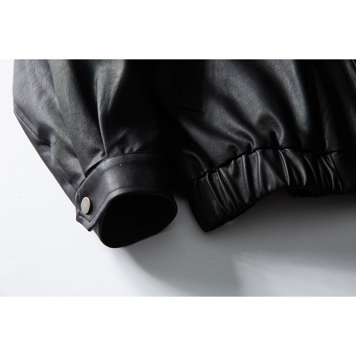 Close-up of a black jacket's snap-button cuff and gathered elastic hem.