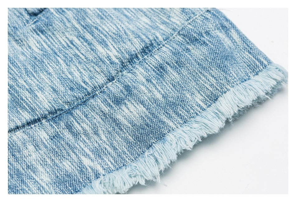 Close-up of light blue washed denim with a frayed raw hem.