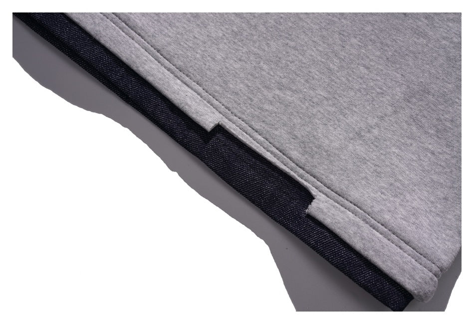 Close-up of a heather-gray garment hem layered over a dark navy fabric edge.