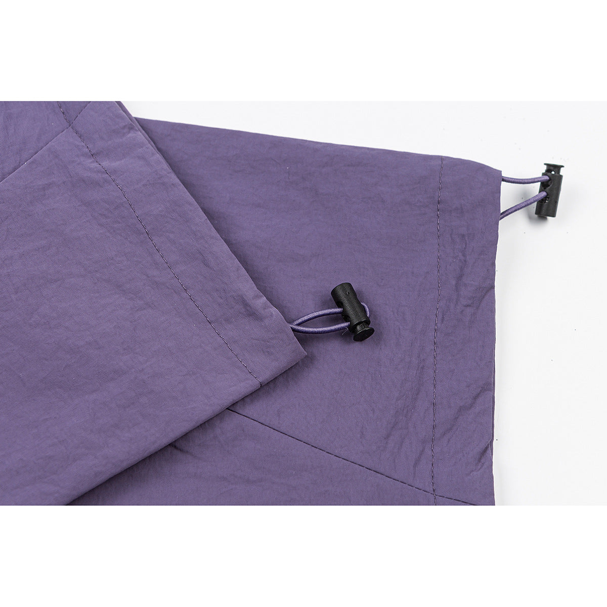Close-up of purple pants with adjustable hem cords and black cord locks.