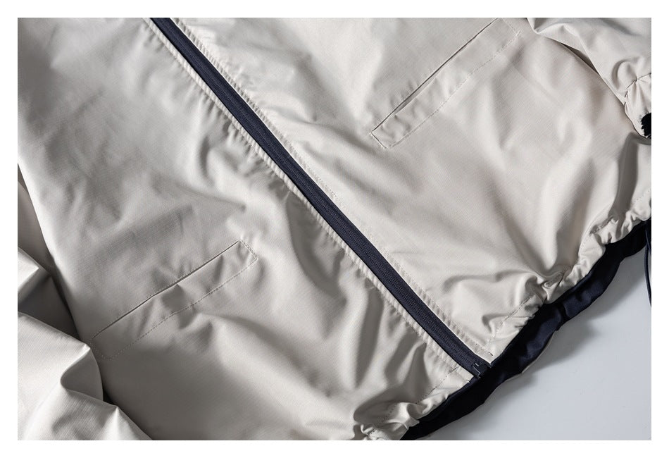 Close-up of an ivory jacket's front zipper, welt pockets, and gathered hem.