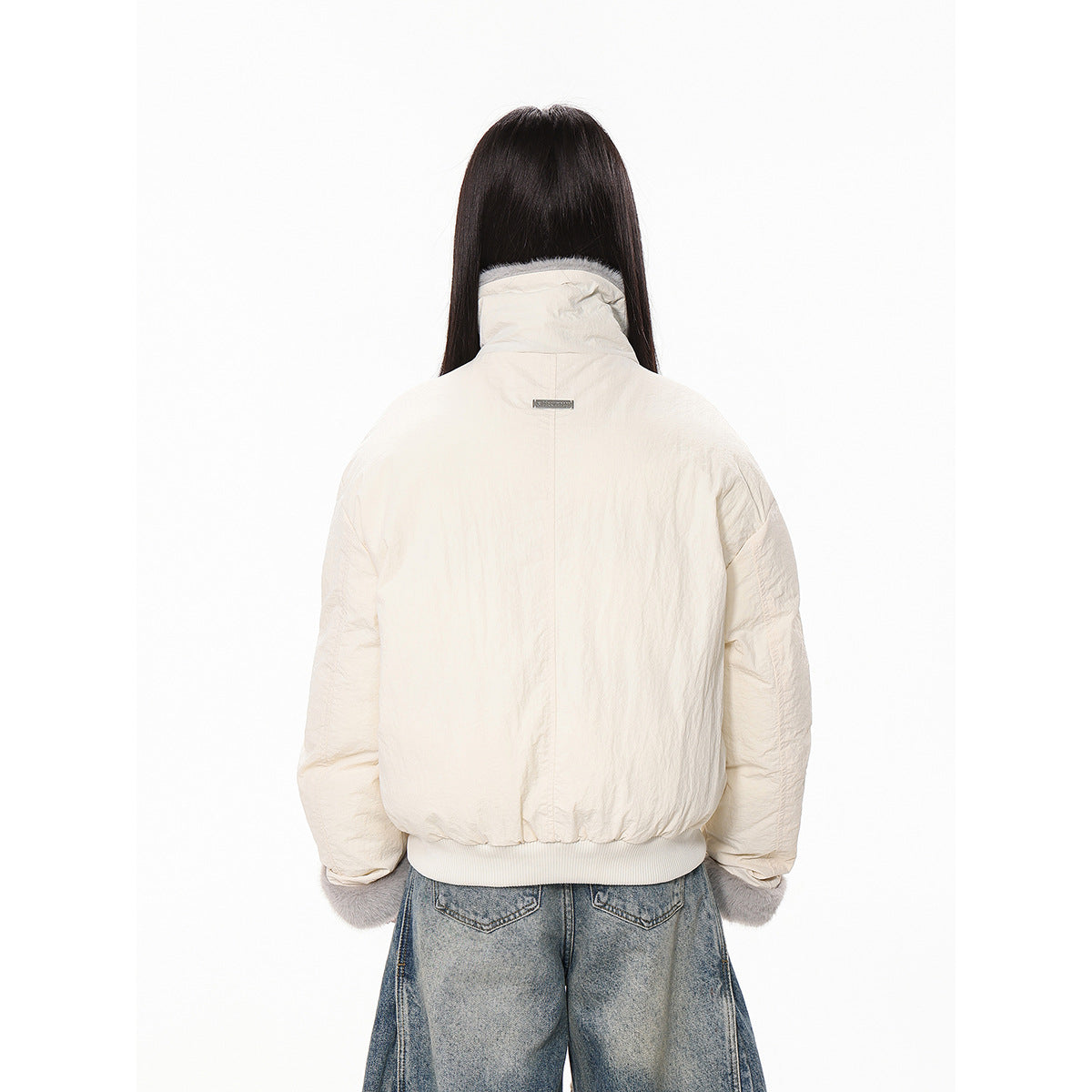 Back view of the ivory jacket, showing its gathered hem, high collar, and gray faux-fur sleeve cuffs.