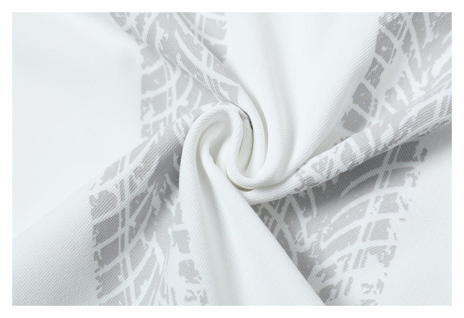 Close-up of white fabric with a pale gray geometric pattern, twisted into a soft spiral.