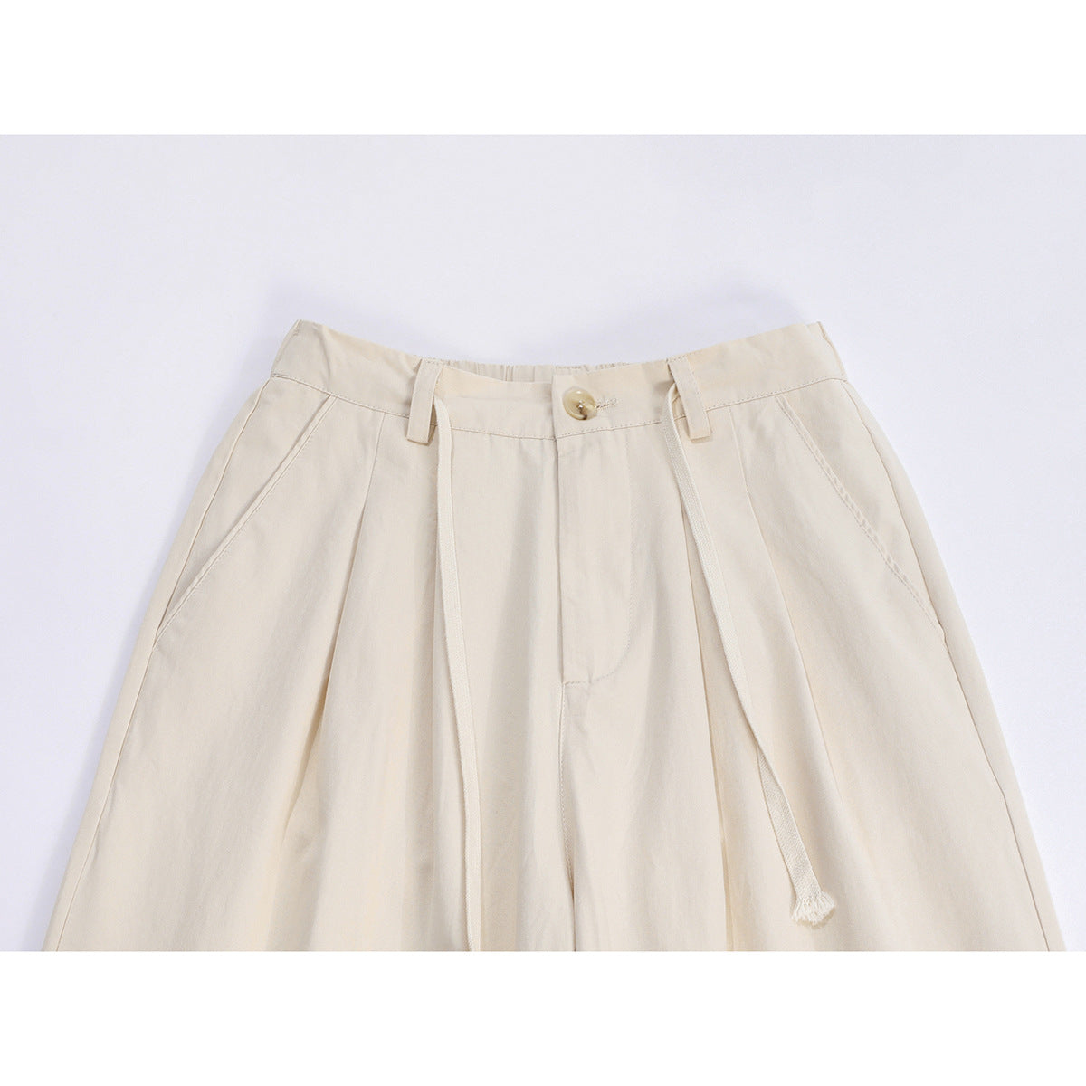 Close-up front view of ivory wide-leg trousers with pleats, belt loops, a button, and a long drawstring.