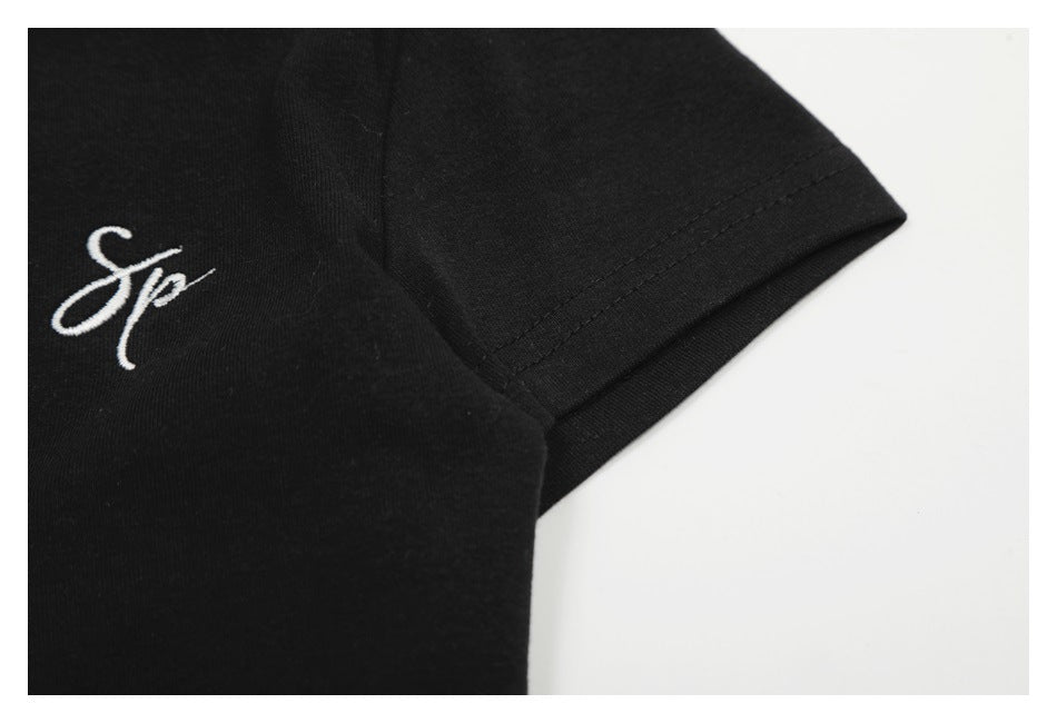 Close-up of a short sleeve hem and white script embroidery on the black top.