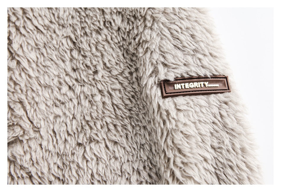 Close-up of a small rectangular brown patch reading “INTEGRITY” on plush gray fabric.