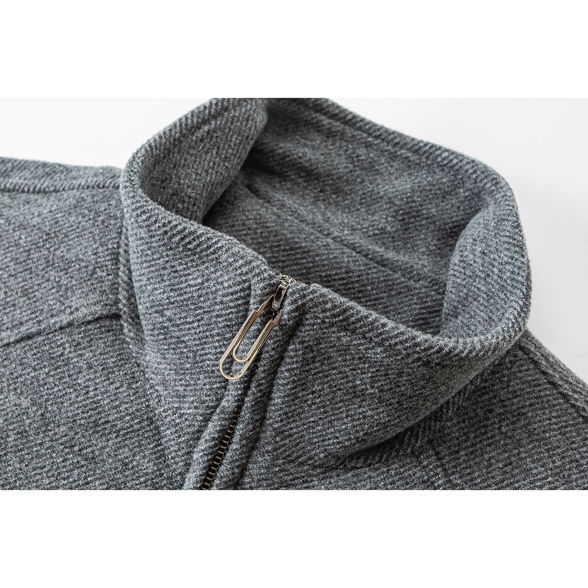 Close-up of a gray textured jacket's high collar, metal zipper pull, and front zipper.