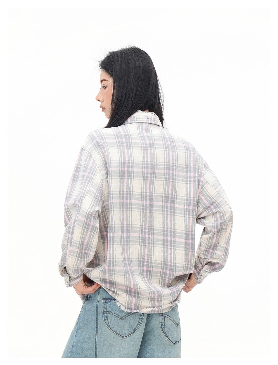 Model turned away to show the back of a cream, gray and pale pink plaid shirt with a frayed hem.