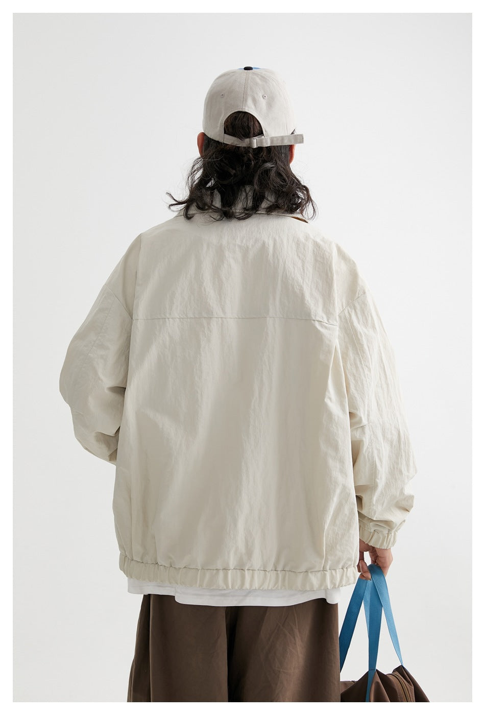 Back view of a model wearing an ivory jacket with a plain back and gathered hem.