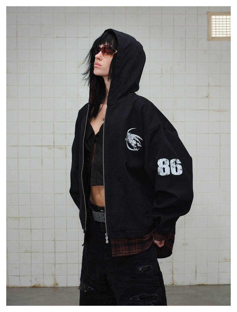 Angled view of a model wearing a black hooded jacket with a white chest graphic, number 86 on the sleeve, and plaid hem.