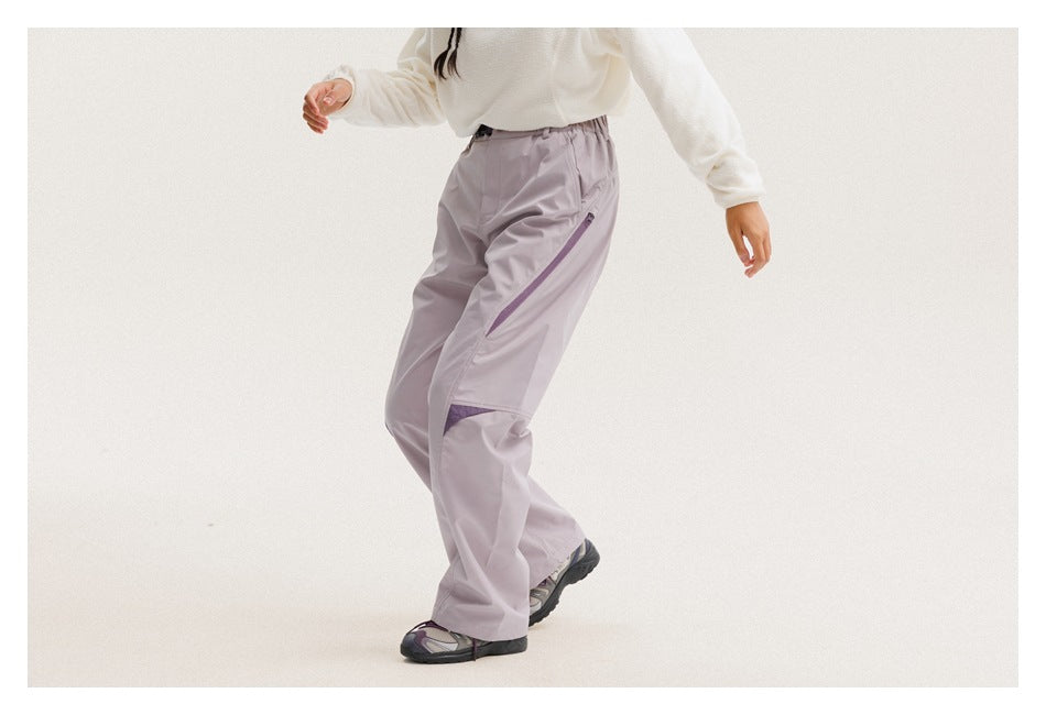 Side view of a person wearing pale lavender pants with a diagonal purple zip pocket and knee accents.