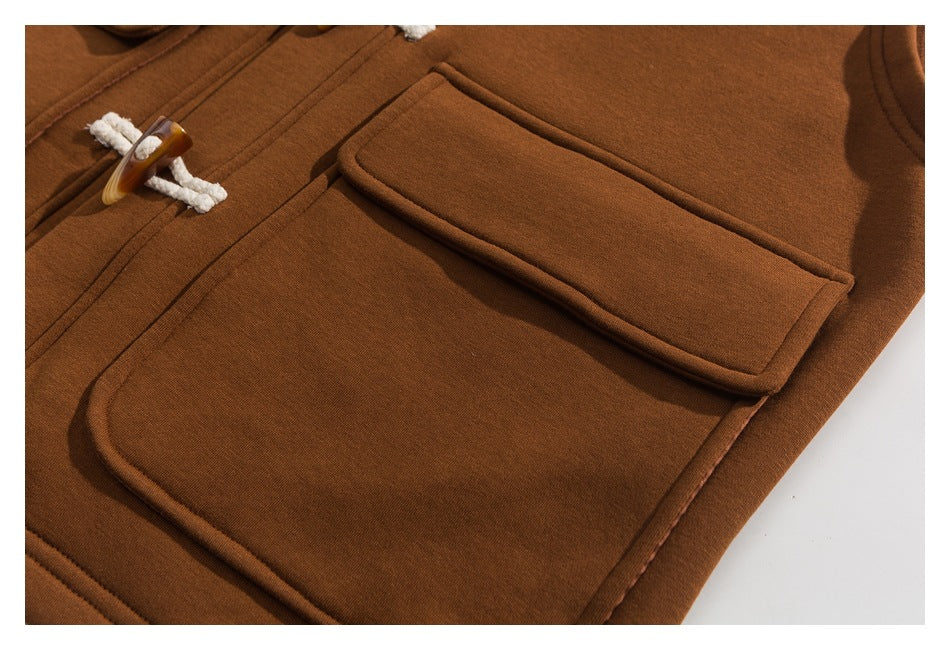 Close-up of a rust-brown coat showing its large rounded patch pocket and toggle closure.