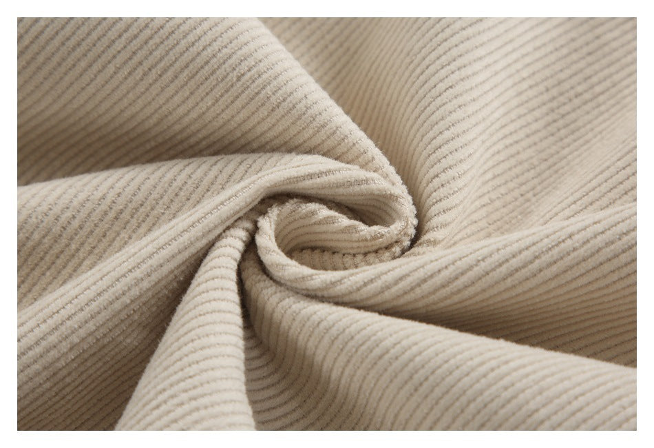Close-up of beige ribbed fabric gathered into folds, showing its textured surface.
