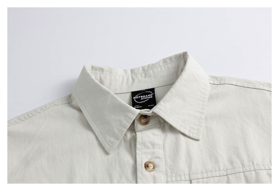 Close-up of an off-white button-up shirt collar, front buttons, and sewn-in neck label.